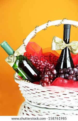 Gift basket with wine on orange background