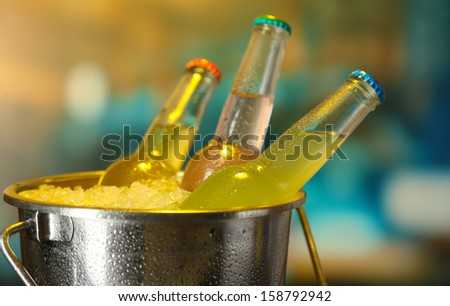 Bottled drinks in ice bucket on bright background