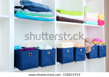 Blue textile boxes with towels and clothes in white shelves