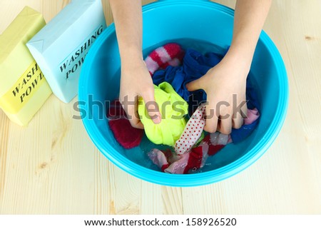 Hand washing in plastic bowl on wooden table close-up