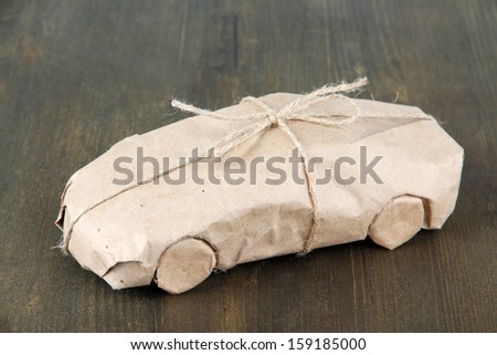 Car wrapped in brown kraft paper, on wooden background