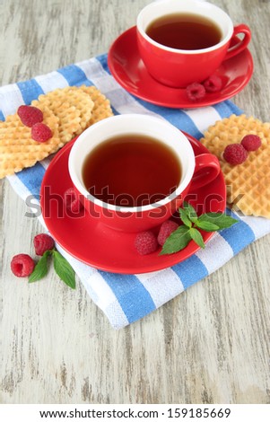 Cups of tea with cookies and raspberries on table close-up