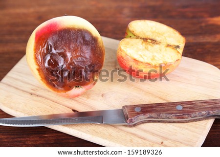 Rotten apples on wooden board on table