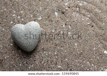 Grey stone in shape of heart, on sand background