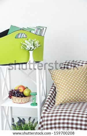 Magazines and folders in green box on shelf in room