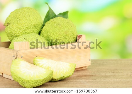 Osage Orange fruits (Maclura pomifera) in crate, on wooden table, on nature background