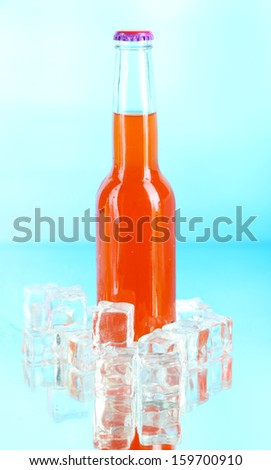 Drink in glass bottle with ice cubes on blue background