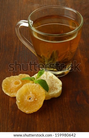 Transparent cup of green tea with candied fruit on wooden background