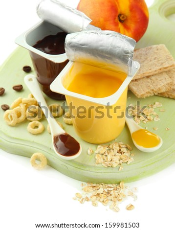 Tasty desserts in open plastic cups and honey combs, fruits and flakes on wooden board isolated on white