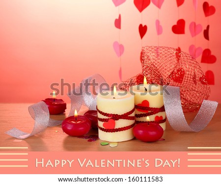 Candles for Valentine Day on wooden table on red background