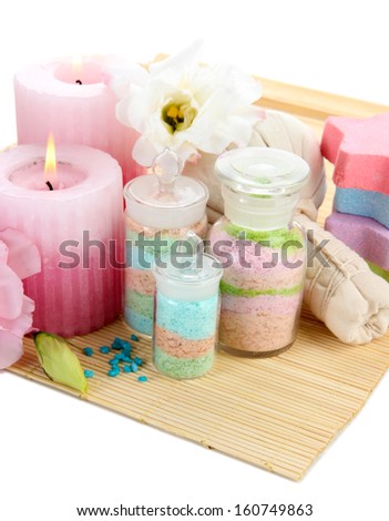 Aromatic salts in glass bottles and herbal compress balls for spa treatment, on bamboo mat,  isolated on white