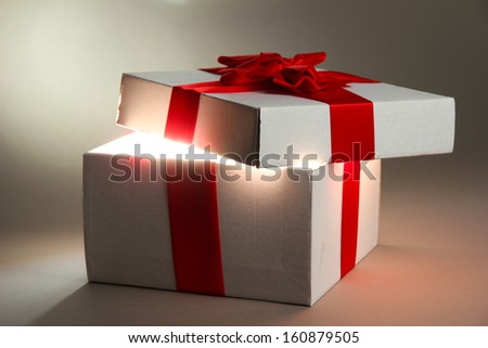 Gift box with bright light on it on grey background