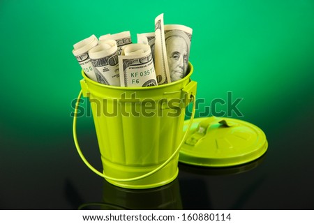 Money in  trash can, on dark background