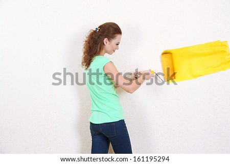 Young woman paints wall in new flat