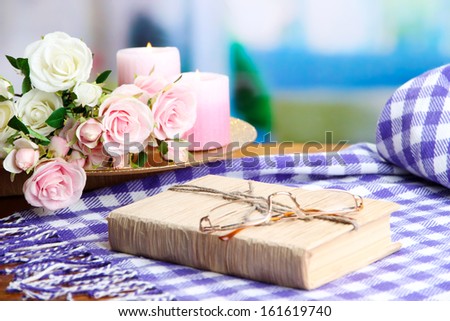 Composition with old book, eye glasses, candles, flowers and plaid on bright background