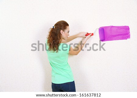 Young woman paints wall in new flat