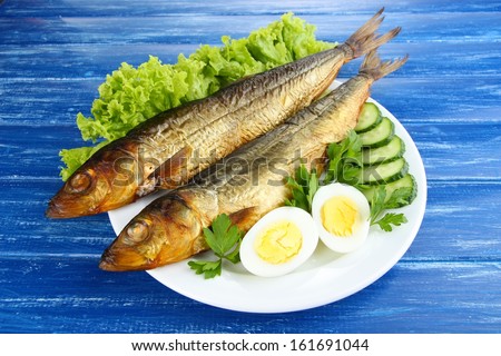 Smoked fish on plate on wooden table