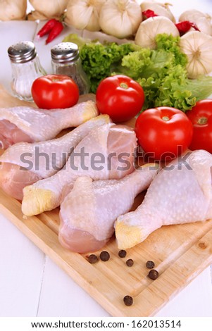 Raw chicken legs on wooden board close up
