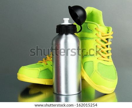 Sports bottle and sneakers on grey background