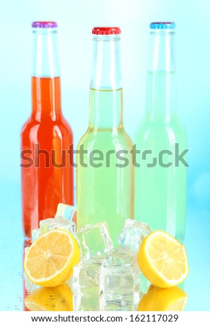 Drinks in glass bottles with ice cubes on blue background