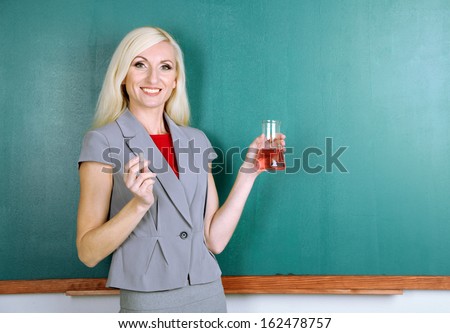 Chemistry teacher writes in chalk on blackboard close-up