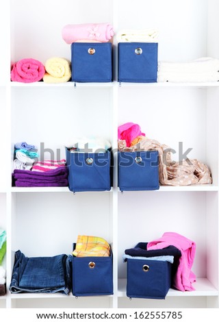 Blue textile boxes with towels and clothes in white shelves
