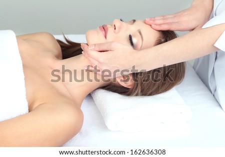 Beautiful young woman during facial massage in cosmetic salon close up