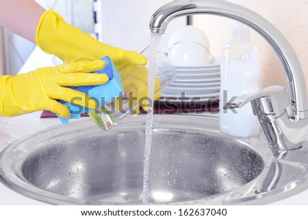Close up hands of woman washing dishes in kitchen