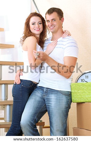 Young couple with keys to your new home on staircase background