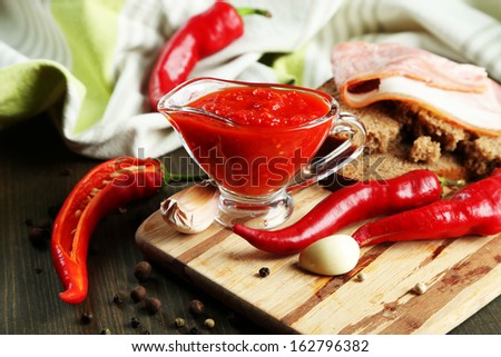 Composition with salsa sauce on bread,, red hot chili peppers  and garlic, on napkin,  on wooden background