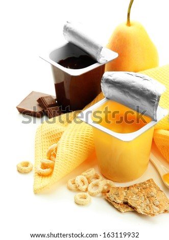 Tasty desserts in open plastic cups and fruits and flakes on napkin, isolated on white