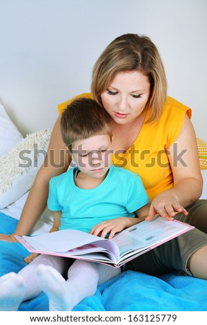 Little boy with mom read book in bed