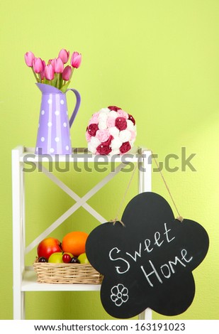 Composition of various home furnishing on white shelf on green wall background