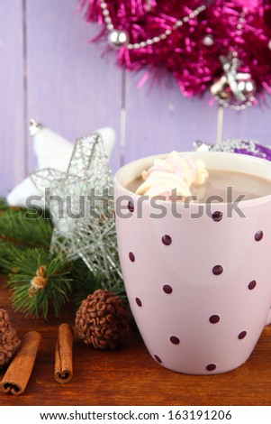 Cup of hot cacao with chocolates and Christmas decorations on table on wooden background
