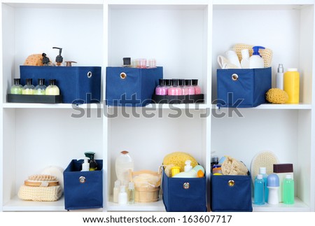 Blue textile boxes with cosmetic products for personal care in white shelves