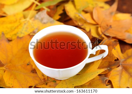 Cup of hot beverage, on yellow leaves background
