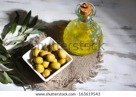Olive oil and olives in bowl on sackcloth on wooden table
