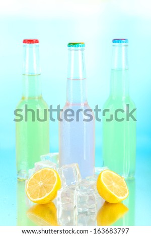 Drinks in glass bottles with ice cubes on blue background