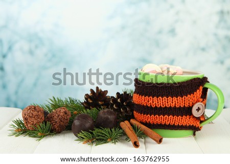Cup of hot cacao with chocolates and fir branches on table on bright background