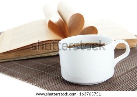 Cup of coffee and book on bamboo mat on white background