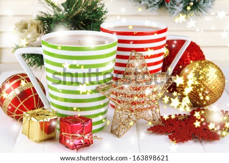Cups of hot cacao with Christmas decorations on table on wooden background