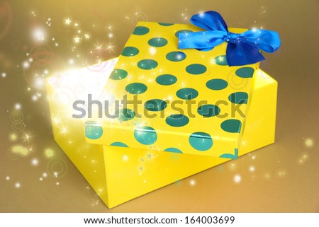 Gift box with bright light on it on yellow background