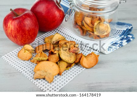 Fresh apples and dried apples in glass jar, on color wooden background