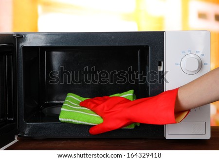 Hand with microfiber cleaning  microwave oven, on bright background