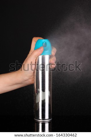 Sprayed air freshener in hand isolated on black