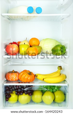 Milk bottles, vegetables and fruits in open refrigerator. Weight loss diet concept.