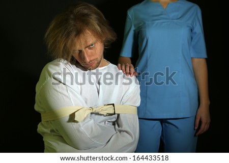 Mentally ill man in strait-jacket on black background