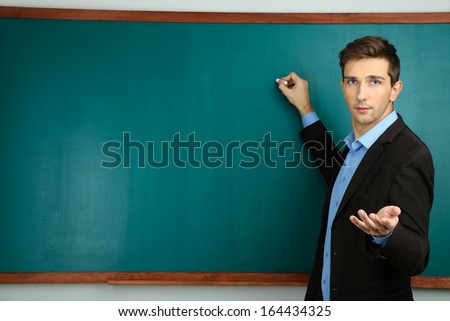 Young teacher near chalkboard in school classroom Young teacher near chalkboard in school classroom