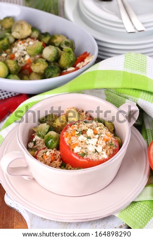Stuffed tomatoes in pan and bowl on wooden table close-up