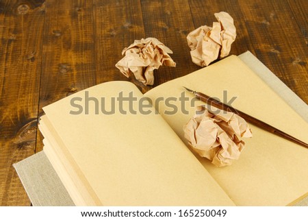 Crumpled paper balls with notebook and ink pen on wooden background